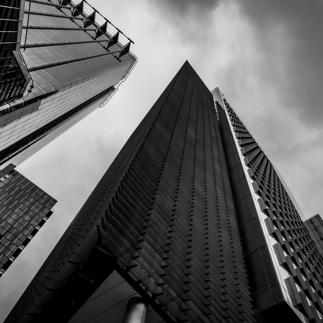 A black and white photo exterior, from ground looking up, of a London office block.