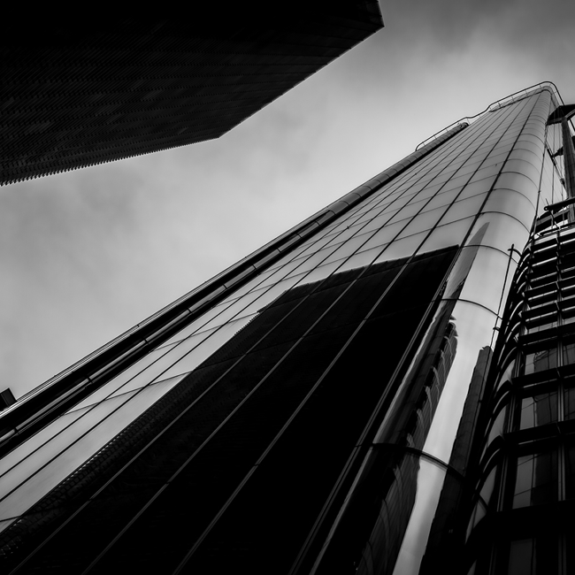 A black and white photo exterior, from ground looking up, of a London office block.