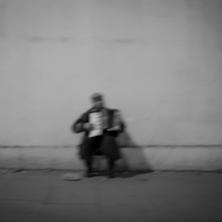 An out of focus black and white photo of an accordion player on streets of London, England