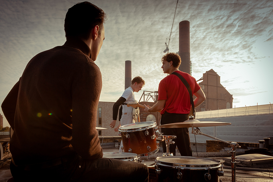 3 male members of a music band on a roof with instruments