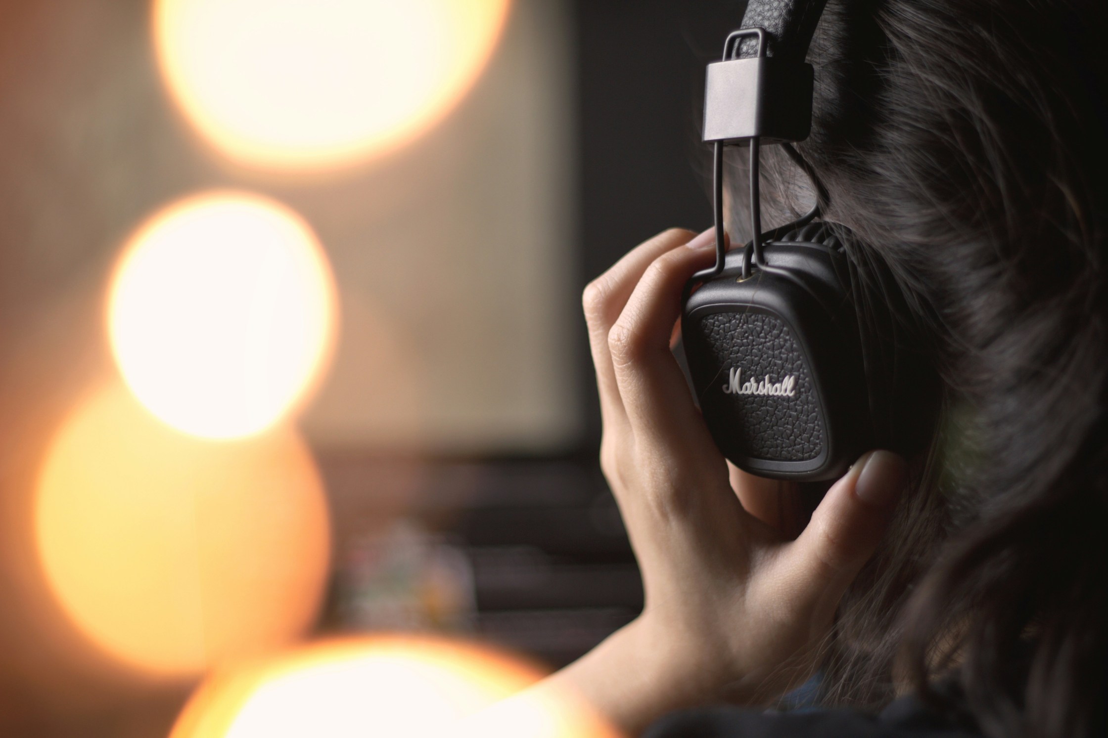 back of head, wearing headphones and holding with hands.
